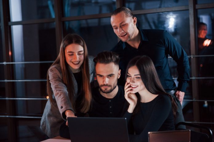 Official clothing. Team of young business people works on their project at night time in the office