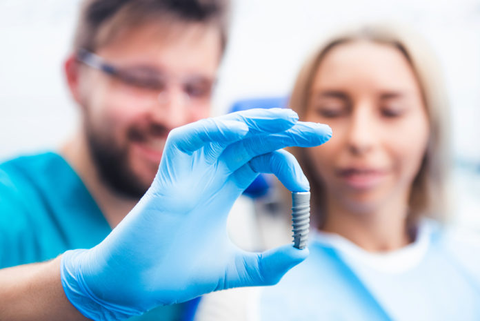Dentist showing gray implant model